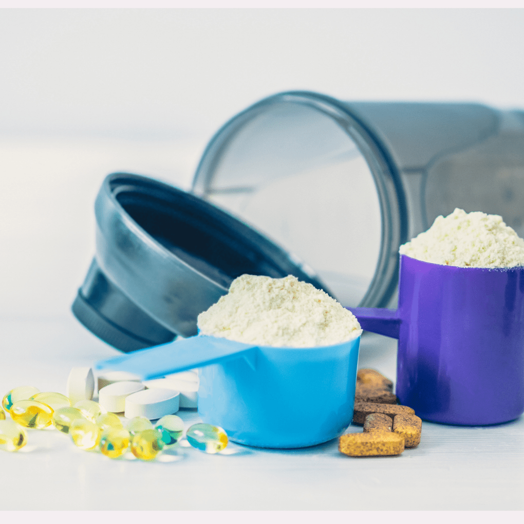 Eine Hand, die eine Vielzahl von Nahrungsergänzungsmitteln hält, darunter verschiedene Kapseln und Tabletten in unterschiedlichen Farben für Sport